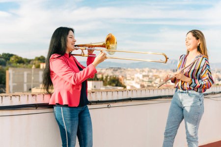Female trombonist and flutist laughing at a rehearsal
