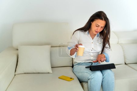 Photo for Middle-aged Romanian businesswoman teleworking from her home sofa - Royalty Free Image