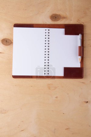 Foto de Blank notepad in leather cover with graphite pencil lie on wooden desk - Imagen libre de derechos