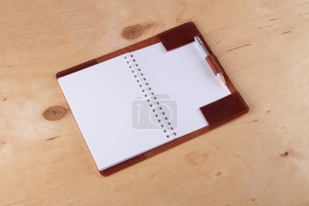 Foto de Blank scratchbook in leather cover with graphite pencil lie on wooden desk - Imagen libre de derechos