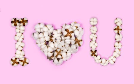 Foto de Phrase " i love u " with heart shape instead of the word love made from cotton flowers on pink background - Imagen libre de derechos