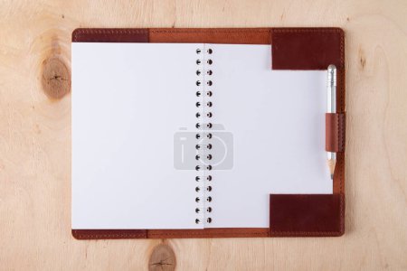 Foto de Cuaderno de dibujo en blanco en cubierta de cuero con lápiz de grafito se encuentran en el escritorio de madera - Imagen libre de derechos