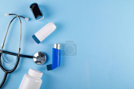 Téléchargez les photos : Vue du dessus du stéthoscope, de l'oxymètre, du flacon de pilules et des inhalateurs sur fond bleu avec espace de copie. Concept de trouble respiratoire causé par l'asthme - en image libre de droit