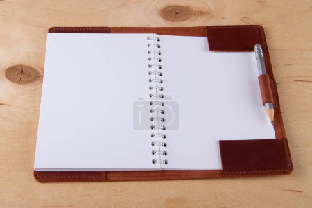 Foto de Revestimiento en blanco en la cubierta de cuero con lápiz de grafito mentira en escritorio de madera - Imagen libre de derechos