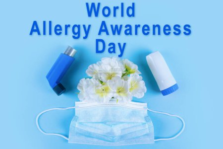 Téléchargez les photos : Journée mondiale de sensibilisation aux allergies célébrée le 16 octobre. Affiche avec inscription bleue, inhalateurs, masque chirurgical et fleurs blanches sur fond bleu clair uni - en image libre de droit