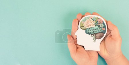 Photo for Hands holding paper head, human brain with flowers, self care and mental health concept, positive thinking, creative mind - Royalty Free Image