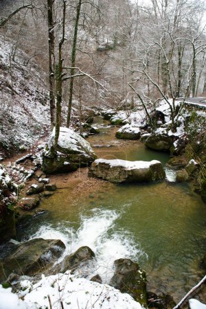 Foto de Scheissendempel waterfall, river Black Ernz with stone bridge covered with snow, Mullerthal trail in Waldbillig, Luxembourg in winter - Imagen libre de derechos