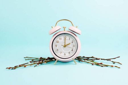 Foto de Alarm clock with pussy willow brances, switch to daylight saving time in spring, summer time changeover - Imagen libre de derechos