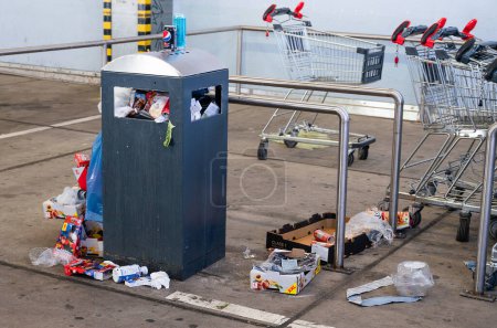 Foto de Basurero desbordante, bote de basura con bolsas de plástico y cartón, centro comercial sucio, Alleencenter en Trier, Alemania - Imagen libre de derechos