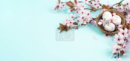 Photo for Colored easter eggs in a bird nest, pink cherry blossoms, holiday greeting card, spring season background - Royalty Free Image