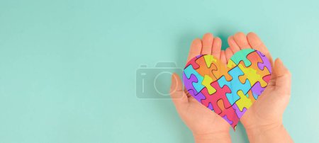 Foto de Trastorno del espectro autista ASD, déficits en la comunicación social y la interacción, las manos en el corazón con coloridas piezas de rompecabezas o rompecabezas - Imagen libre de derechos