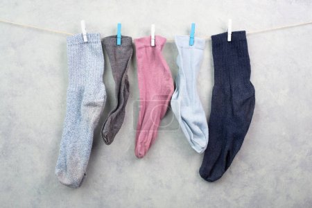 Photo for Lost socks hanging on a clothes line with clothespin, missing sock match after washing, memorial day - Royalty Free Image