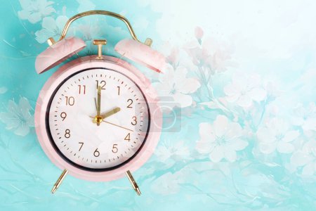 Foto de Reloj despertador con flores de cerezo, cambio a horario de verano en primavera, cambio de horario de verano - Imagen libre de derechos
