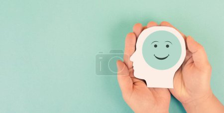 Holding a head with a happy smiling face in the hands, mental health concept, positive thinking, support and evaluation 