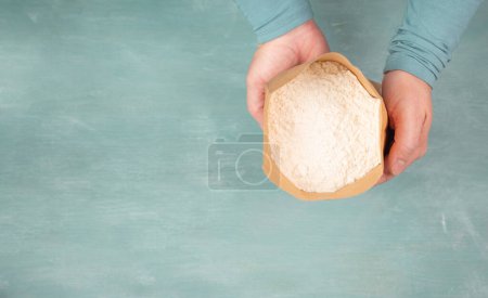 Baker holds paper bag with white wheat flour, baking ingredient for bread, pizza or pastry 
