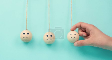 Happy smiling face spread happiness to sad faces, newton cradle concept, mental health and attitude, positive and negative mind, influence emotion, support and depression, pendulum balls