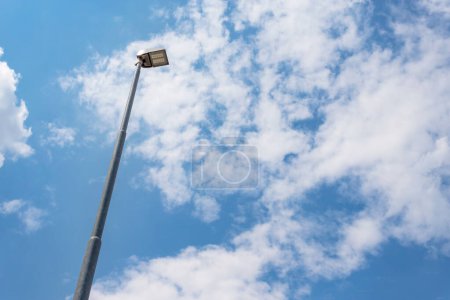Street lamp against blue sky with white clouds. Bottom view.