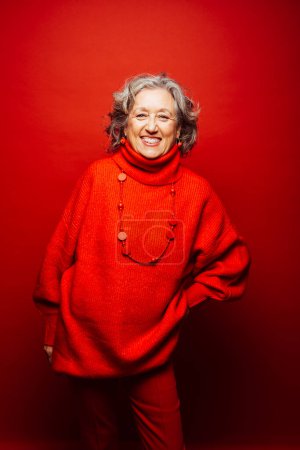 Photo for Senior smiling woman red clothes over a red background - Royalty Free Image