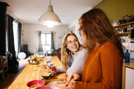 Ein lesbisches Paar bereitet das Frühstück zu und teilt einen intimen Moment miteinander, in der gemütlichen Atmosphäre ihrer Küche zu Hause.