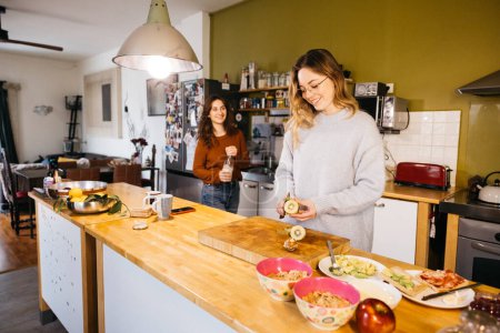 A lesbian couple preparing breakfast and sharing an intimate moment together, in the cozy atmosphere of their kitchen at home.