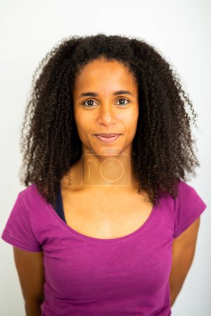Porträt einer lächelnden jungen afrikanisch-amerikanischen Frau, die steht und direkt in die Kamera blickt.