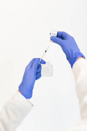 A healthcare professional is drawing a dose of the COVID-19 vaccine into a syringe, emphasizing the preparation process for vaccination and safety measures.