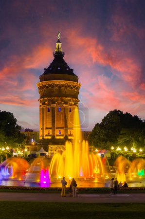 Téléchargez les photos : Mannheim, Allemagne. Vue sur le château d'eau illuminé de Friedrichsplatz au coucher du soleil, avec fontaine créant de splendides effets d'eau et de couleur. Image verticale. 2013-06-16. - en image libre de droit
