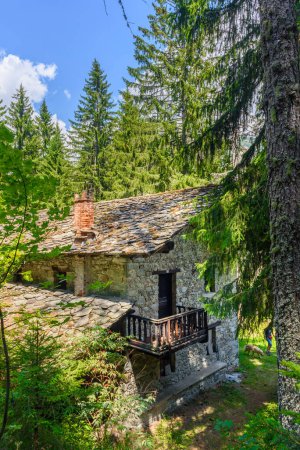 Gressoney, Italien. Ruiniertes Haus im Wald des Parks von Castel Savoia. Vertikales Bild. 27. Juli 2022.