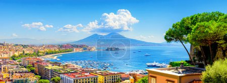Naples, Italy. View of the Gulf of Naples from the Posillipo hill with Mount Vesuvius far in the background and some pine trees in foreground. Banner header horizontal image. 2021-08-31.