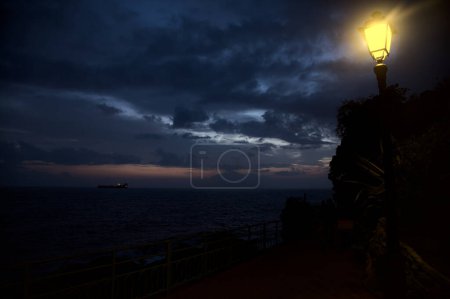 Photo for Panoramic walk with street lights on a cliff by the sea at dusk - Royalty Free Image