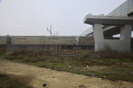 Foto de Ferrocarril con vagones de carga que pasa bajo un viaducto en un día de niebla - Imagen libre de derechos