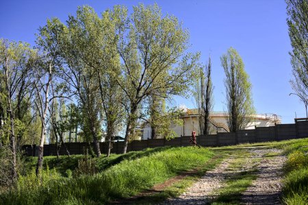 Foto de Camino en un terraplén junto a una pared límite de un complejo industrial en un bosque - Imagen libre de derechos