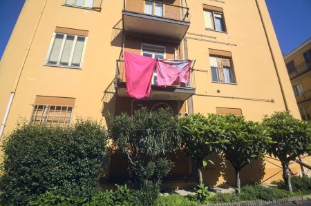 Téléchargez les photos : Façade d'un bâtiment dans une rue d'un village avec des vêtements suspendus sur les balcons - en image libre de droit