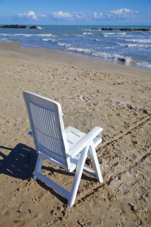 Photo for Deck chair next to water on an empty beach in winter - Royalty Free Image