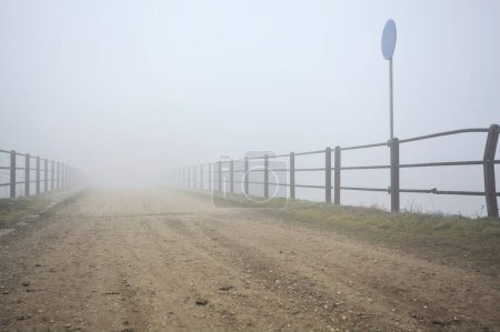 Bridge with worn asphalt on a foggy day