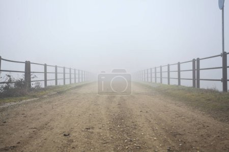 Bridge with worn asphalt on a foggy day