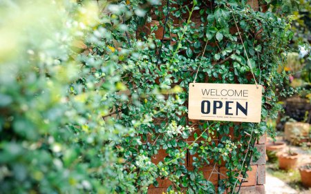 Téléchargez les photos : Panneau ouvert suspendu en face du café avec fond de jardin vert - en image libre de droit