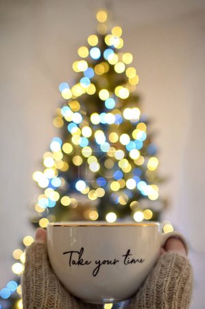 Foto de Conceptual Tómate tu tiempo Chica sosteniendo una taza de té y árbol de Navidad Bokeh - Imagen libre de derechos