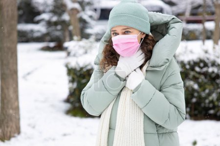 Téléchargez les photos : Jeune femme avec douleur de gorge marchant dans la rue dans un hiver froid da - en image libre de droit