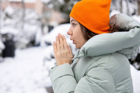 Foto de Mujer joven calentando sus manos en la calle en el frío nevado da - Imagen libre de derechos