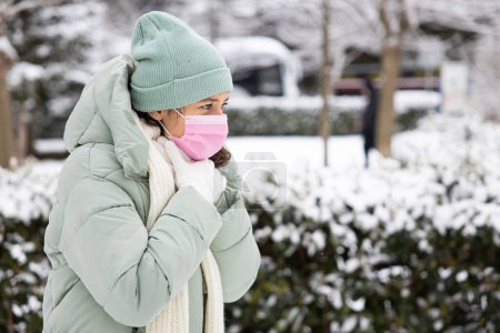 Téléchargez les photos : Young woman with throat pain walking the street in a cold winter da - en image libre de droit
