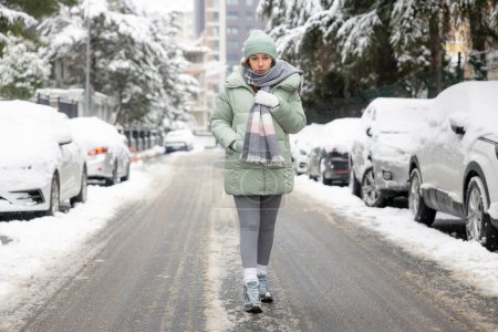 Photo for Young woman walking in the city on a snowy winter day - Royalty Free Image