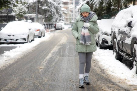 Photo for Young woman walking in the city on a snowy winter day - Royalty Free Image