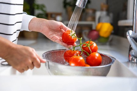 Téléchargez les photos : Femme laver les légumes sur la cuisine Counte - en image libre de droit