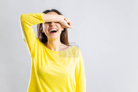 Photo for Laughing young woman covering her eyes with her arm receives good new - Royalty Free Image