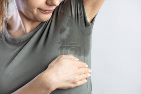 Téléchargez les photos : Young woman with hyperhidrosis sweating. Young woman with sweat stain on her clothes. Excessive sweating problems. - en image libre de droit