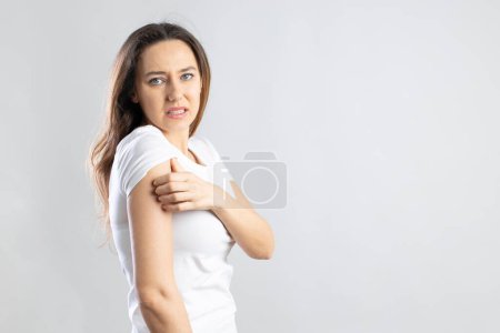 Téléchargez les photos : Jeune femme qui se gratte le bras. Concept problèmes de peau - en image libre de droit