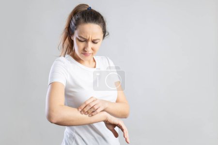 Photo for Young woman scratching her itchy arm. Skin problems concept - Royalty Free Image