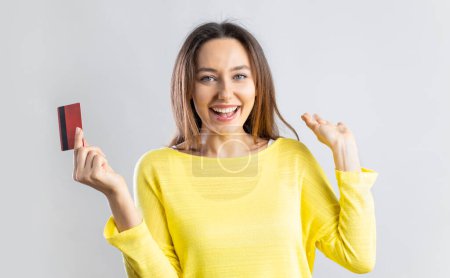 Téléchargez les photos : Joyeux excité jeune femme tenant carte de crédit et geste. Temps de shopping. - en image libre de droit
