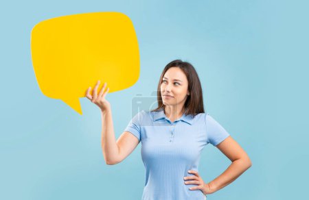 Young woman holding speech bubble isolated on blue wall